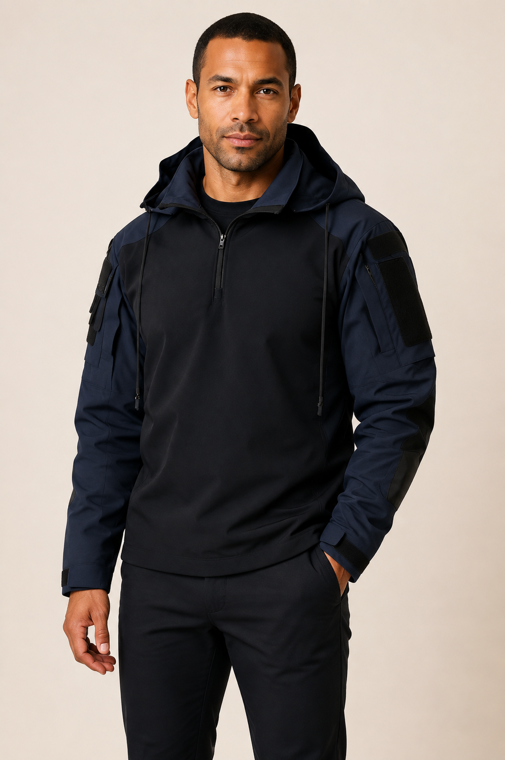 Men's navy and black technical outdoor jacket, worn by model in warm beige studio