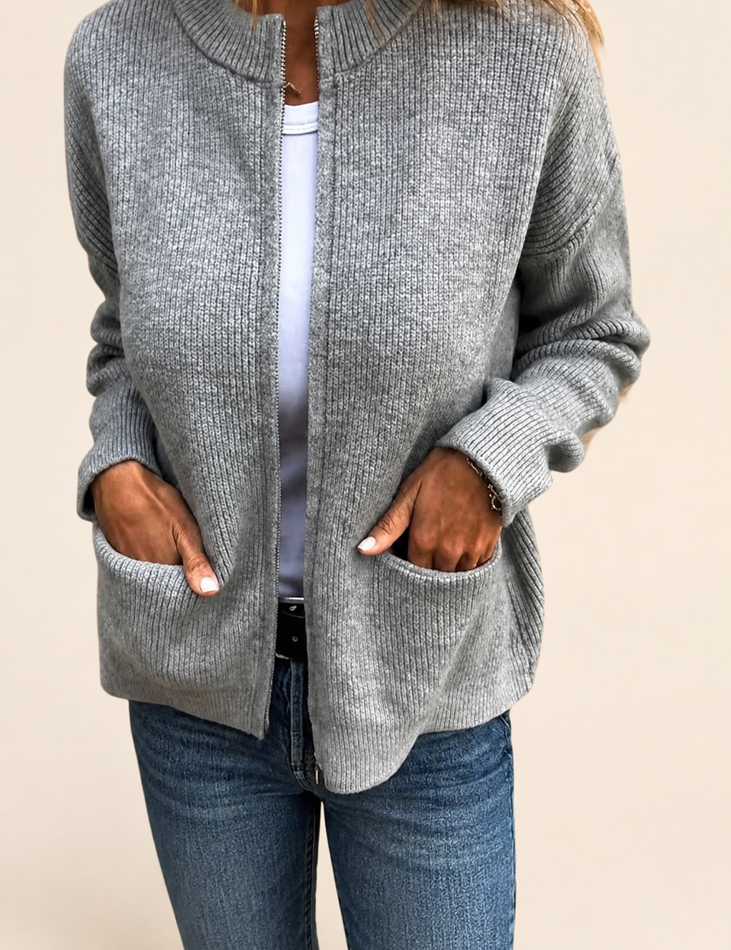 Aino grauer Strickcardigan auf warmem beigem Hintergrund