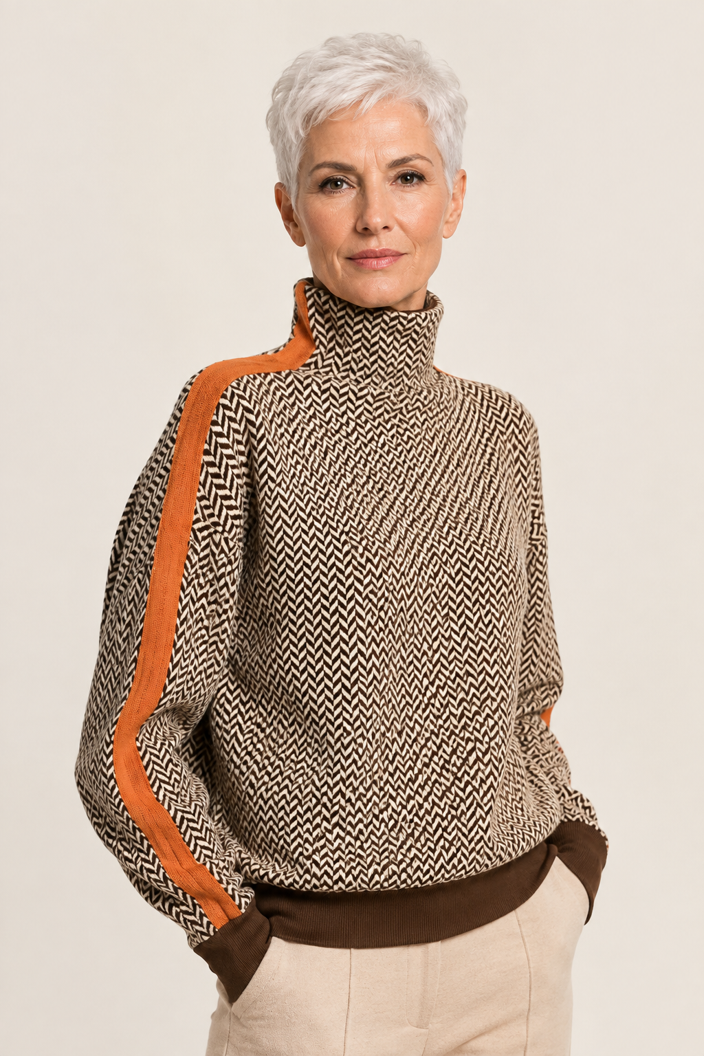 Alisa Fischgrät-Rollkragenpullover mit orangefarbenem Streifen an reifer Frau auf warmem beigem Hintergrund