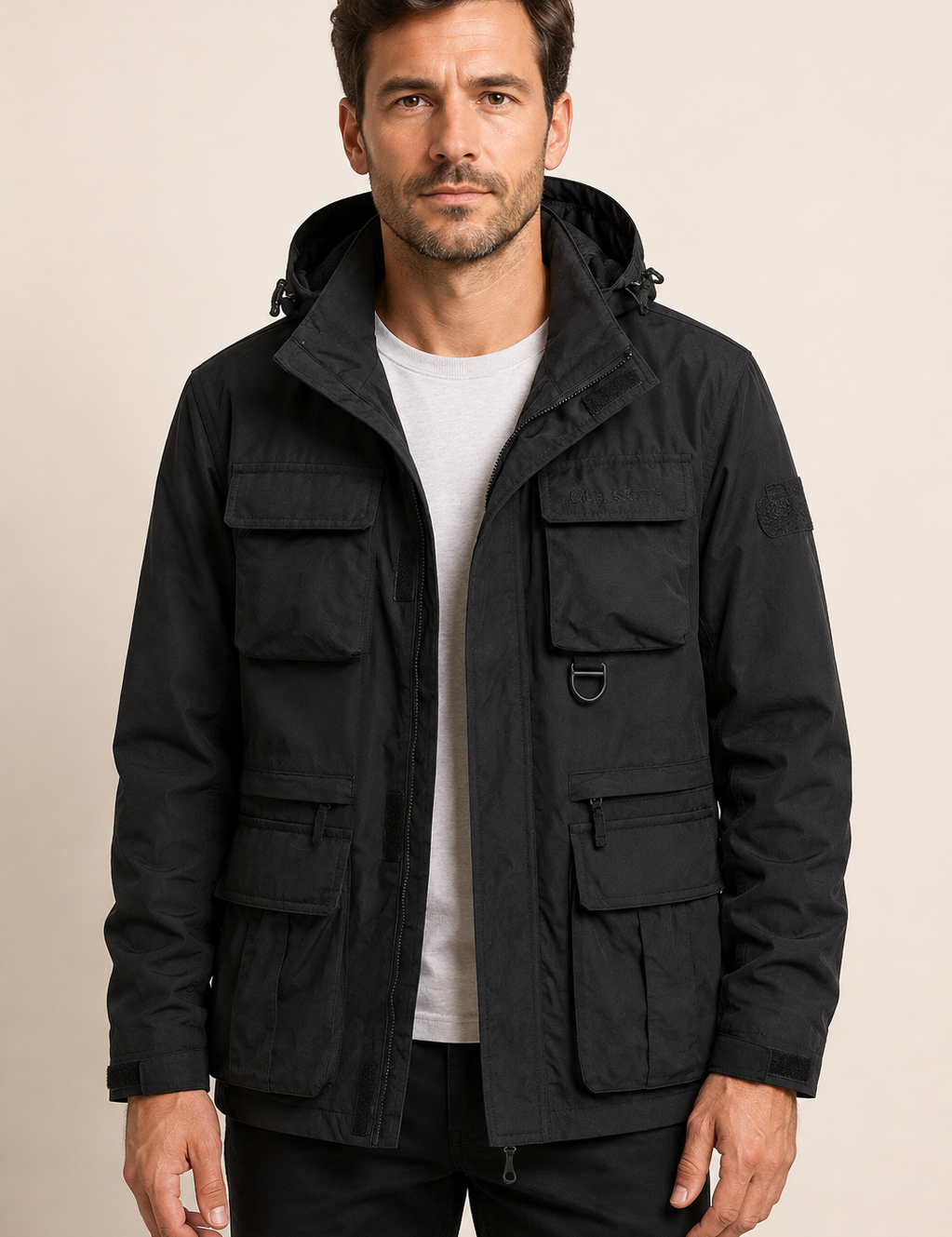Schwarze Multifunktions-Fieldjacke an Mann auf warmem beigem Hintergrund
