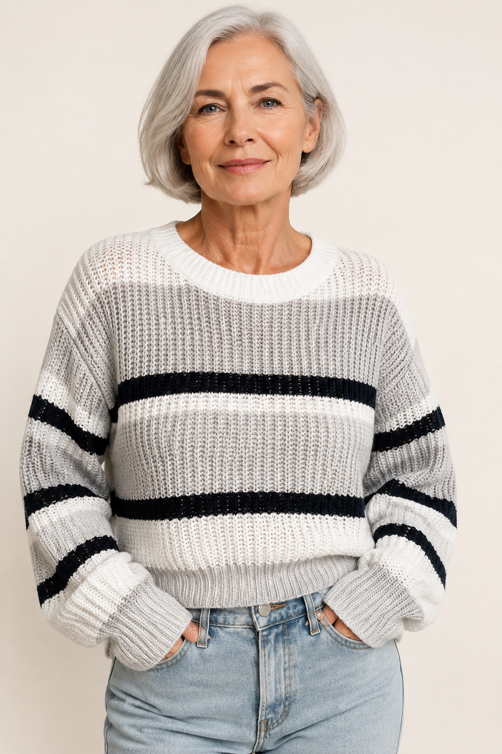 Ema weiß-grau gestreifter Oversize-Pullover an reifer Frau auf warmem beigem Hintergrund