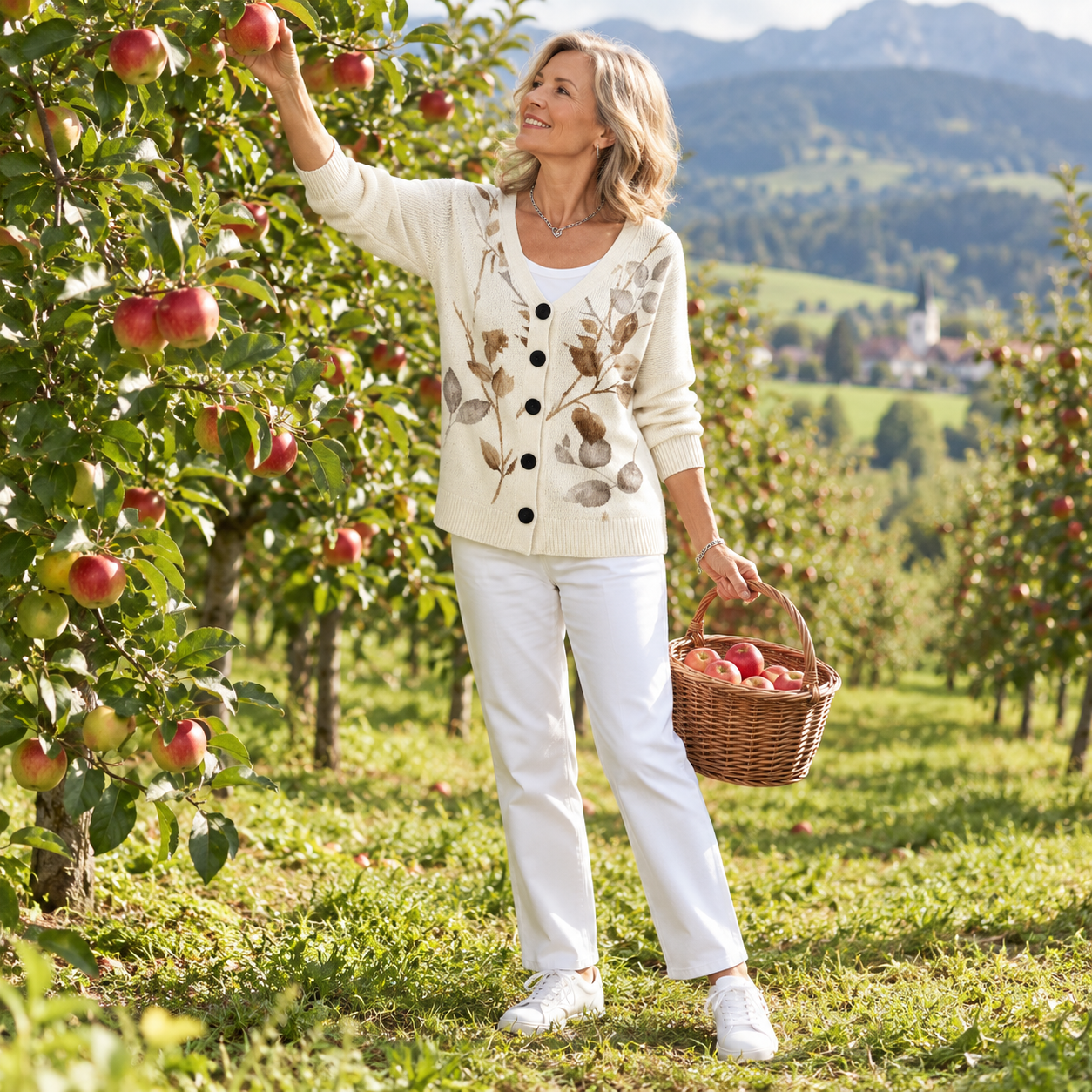Strickjacke Guillemette im Apfelgarten beim Apfelpflücken, Ganzkörperansicht.