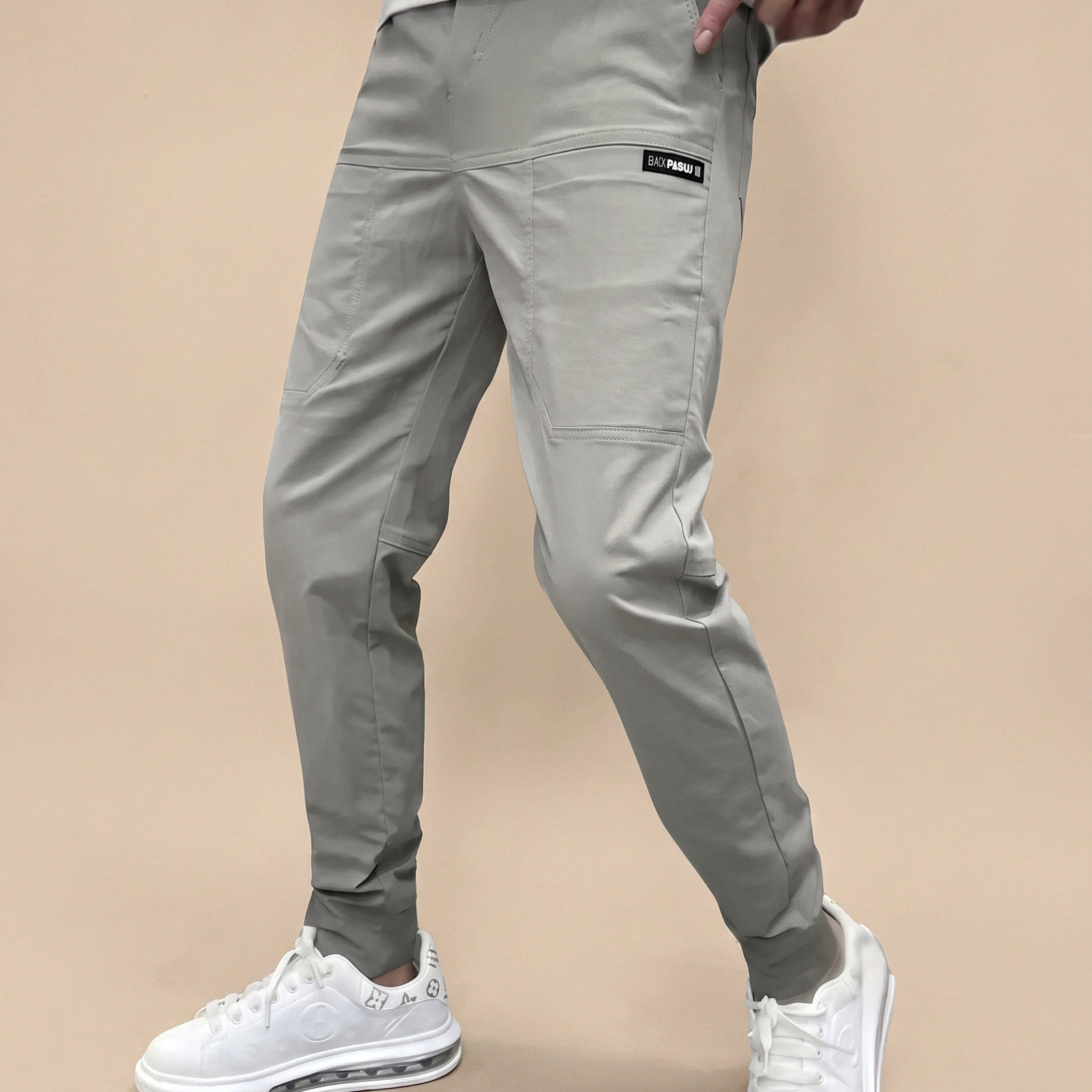 Herrenhose auf warmbeigem Hintergrund #E8DED2 mit männlichem Modell