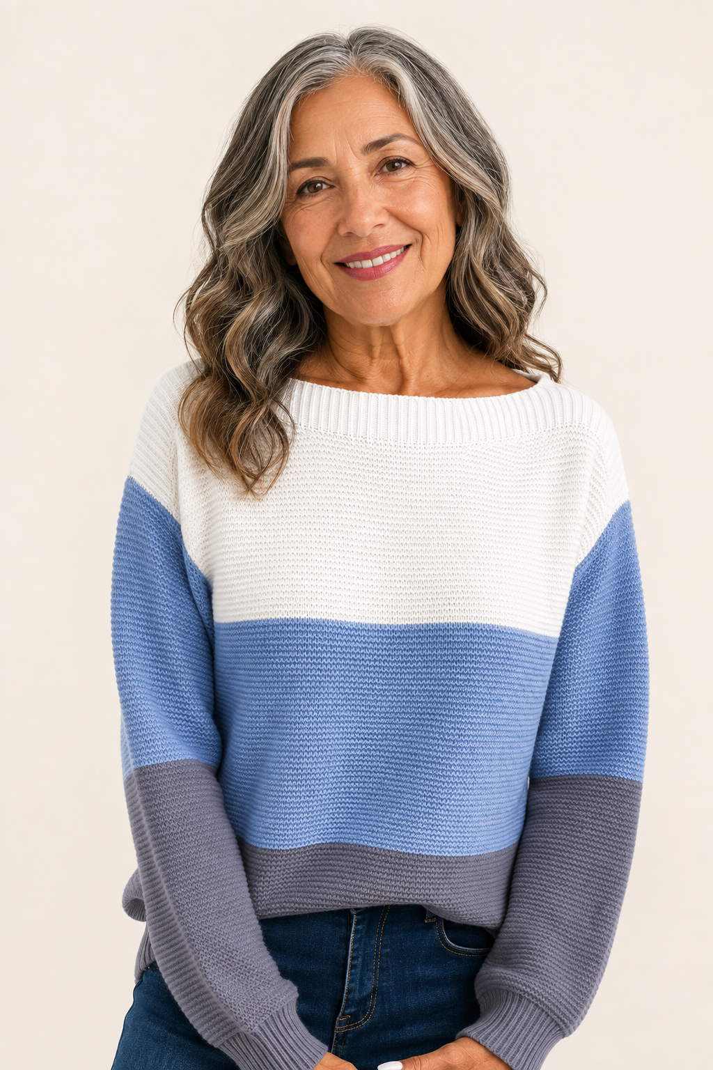 Gabriela-Maria blau-weiß-grauer Colorblock-Pullover an reifer Frau auf warmem beigem Hintergrund