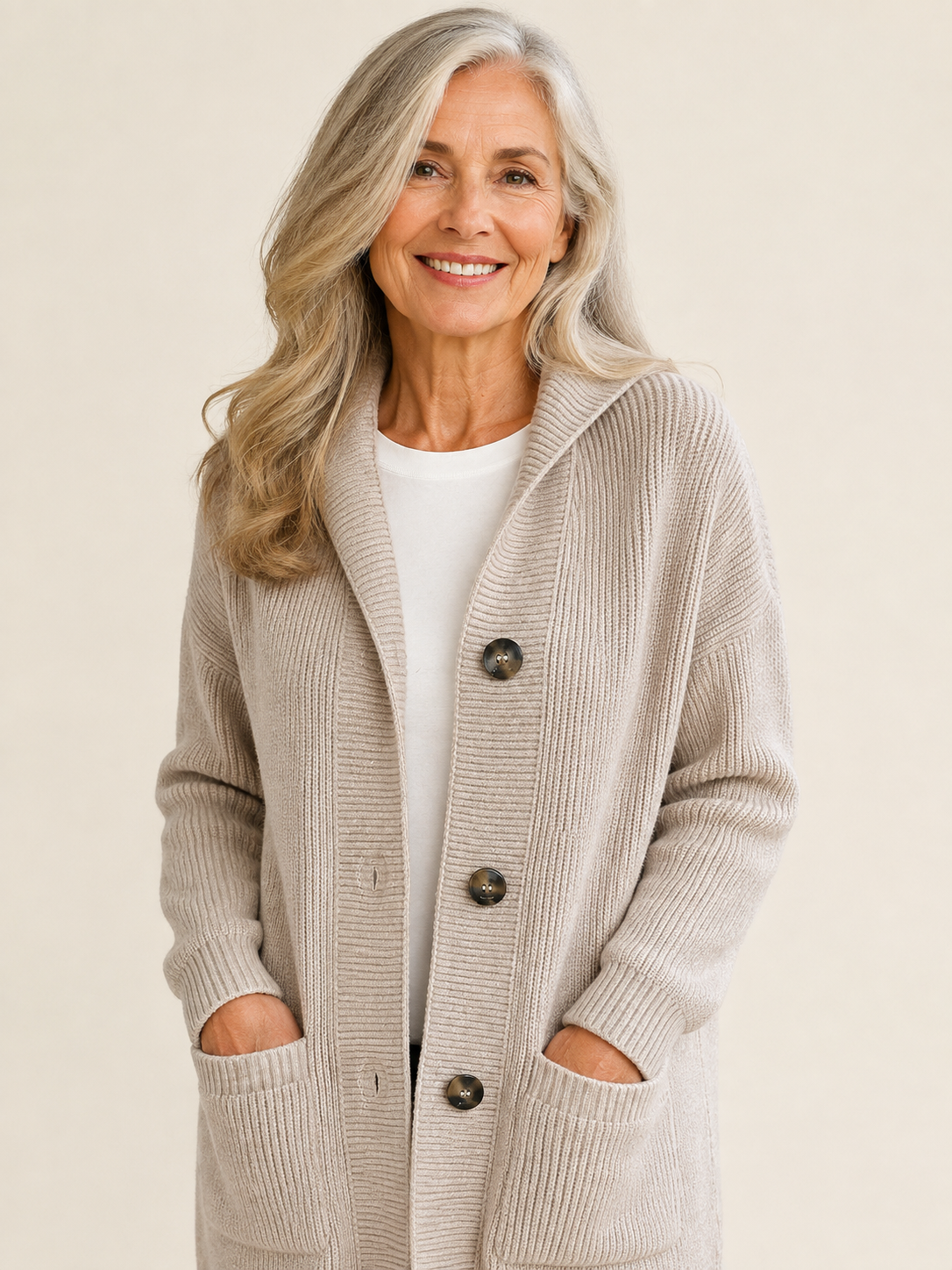 Lange beige Strickjacke mit Knöpfen an reifer Frau auf warmem beigem Hintergrund