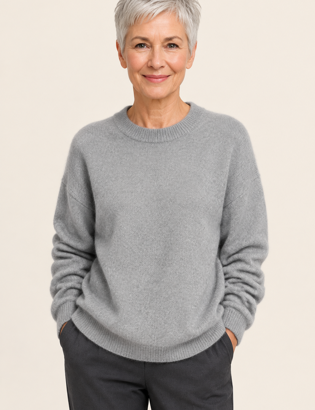 Lia grauer Oversize-Pullover an reifer Frau auf warmem beigem Hintergrund
