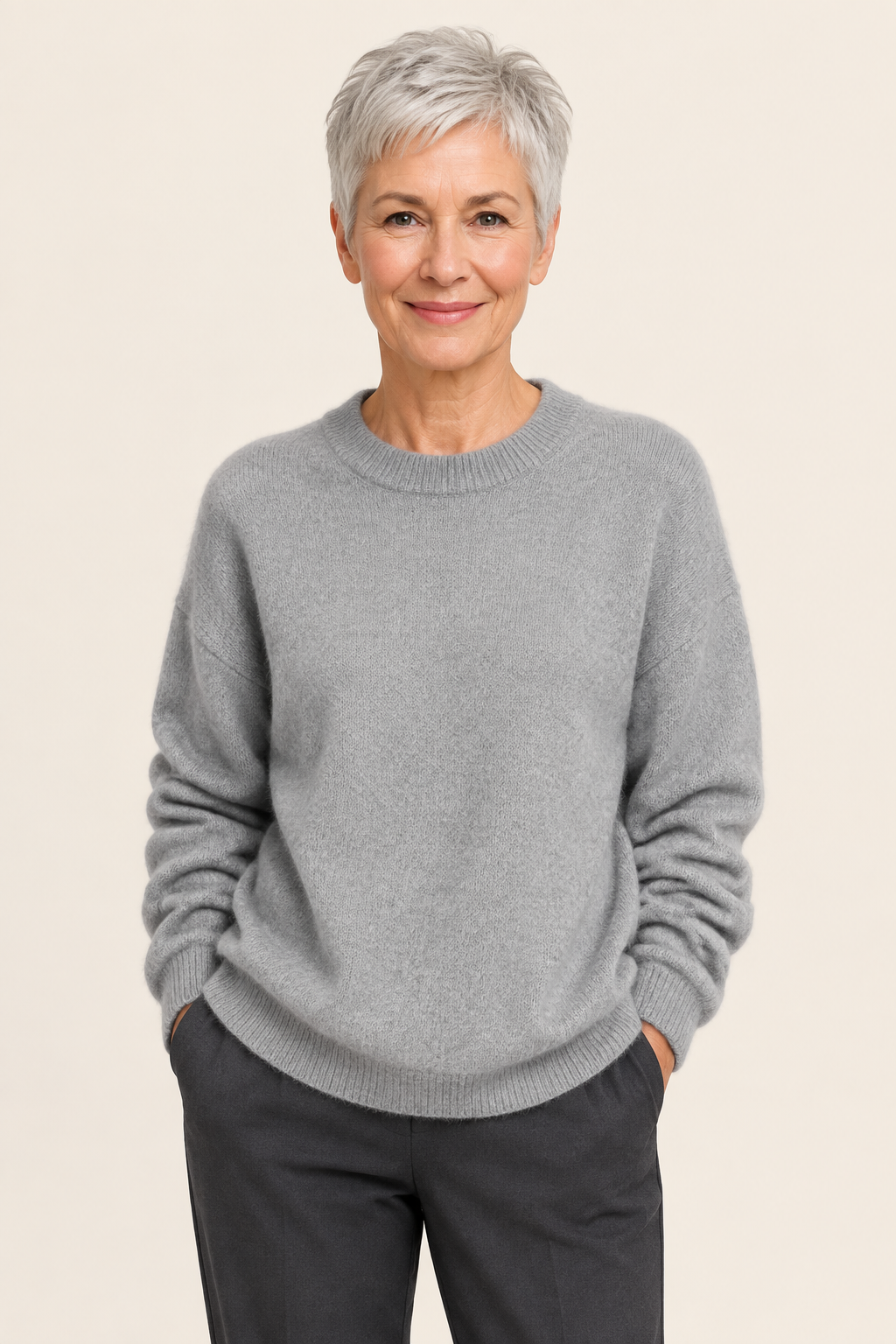 Lia grauer Oversize-Pullover an reifer Frau auf warmem beigem Hintergrund