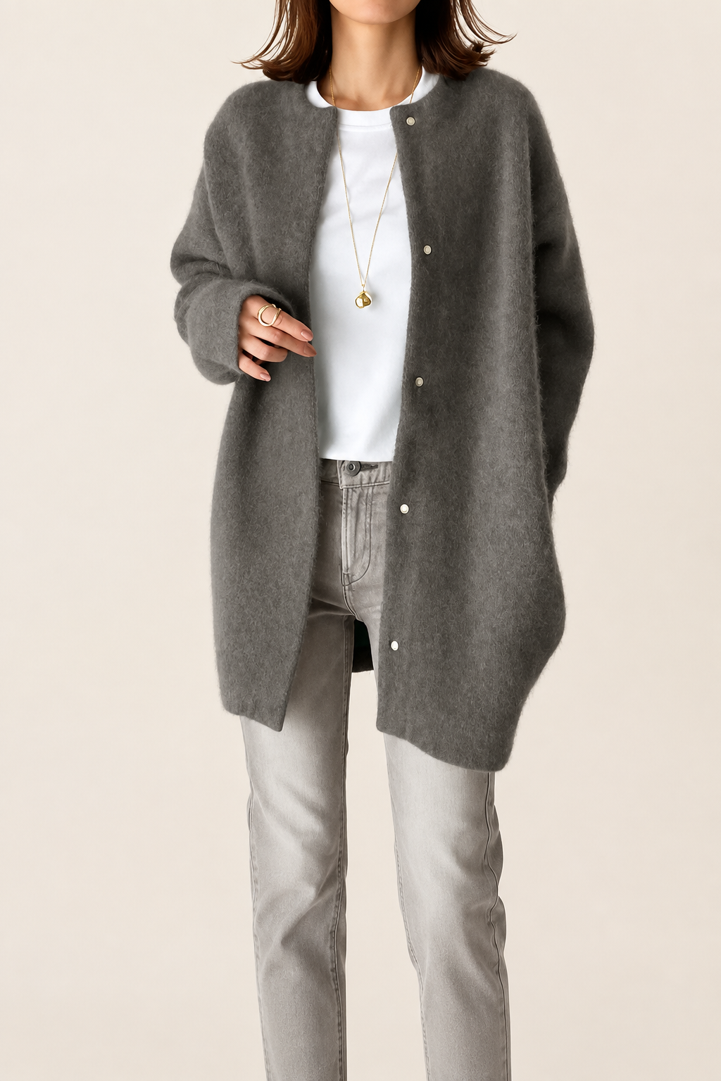 Lockere graue Damen-Strickjacke auf warmem beigem Hintergrund