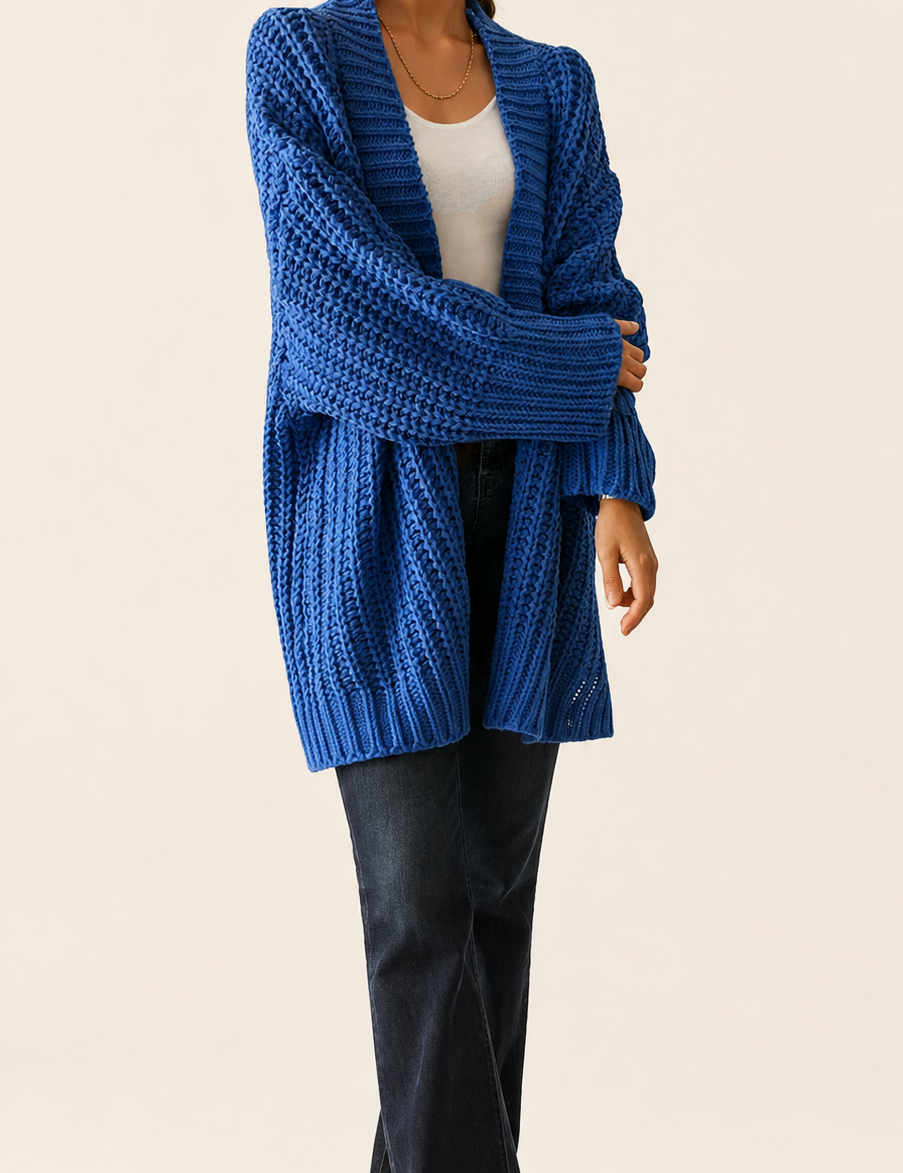 Blaue Oversized Strickjacke auf warmem beigem Hintergrund