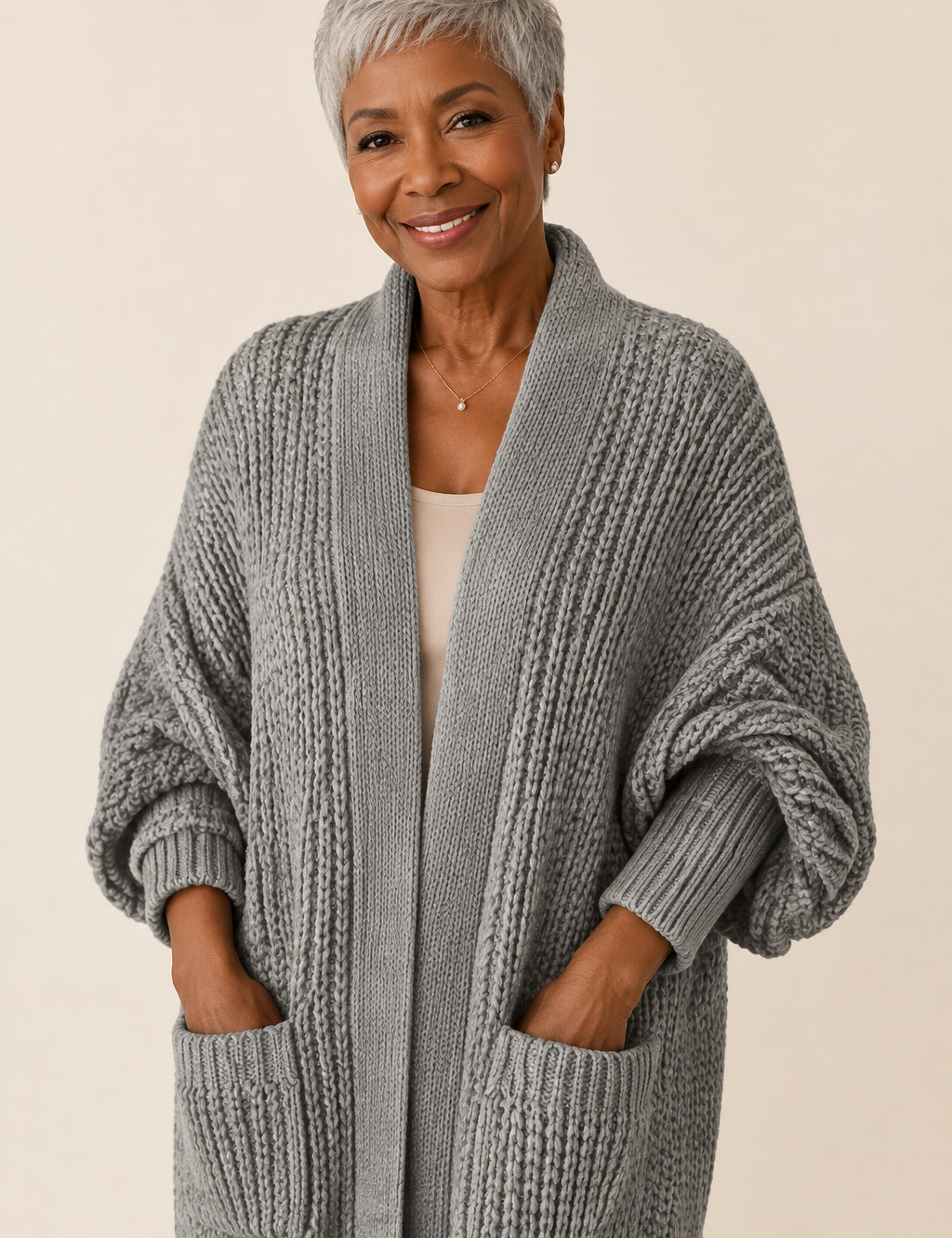 Stela graue lange Strickjacke an reifer Frau auf warmem beigem Hintergrund
