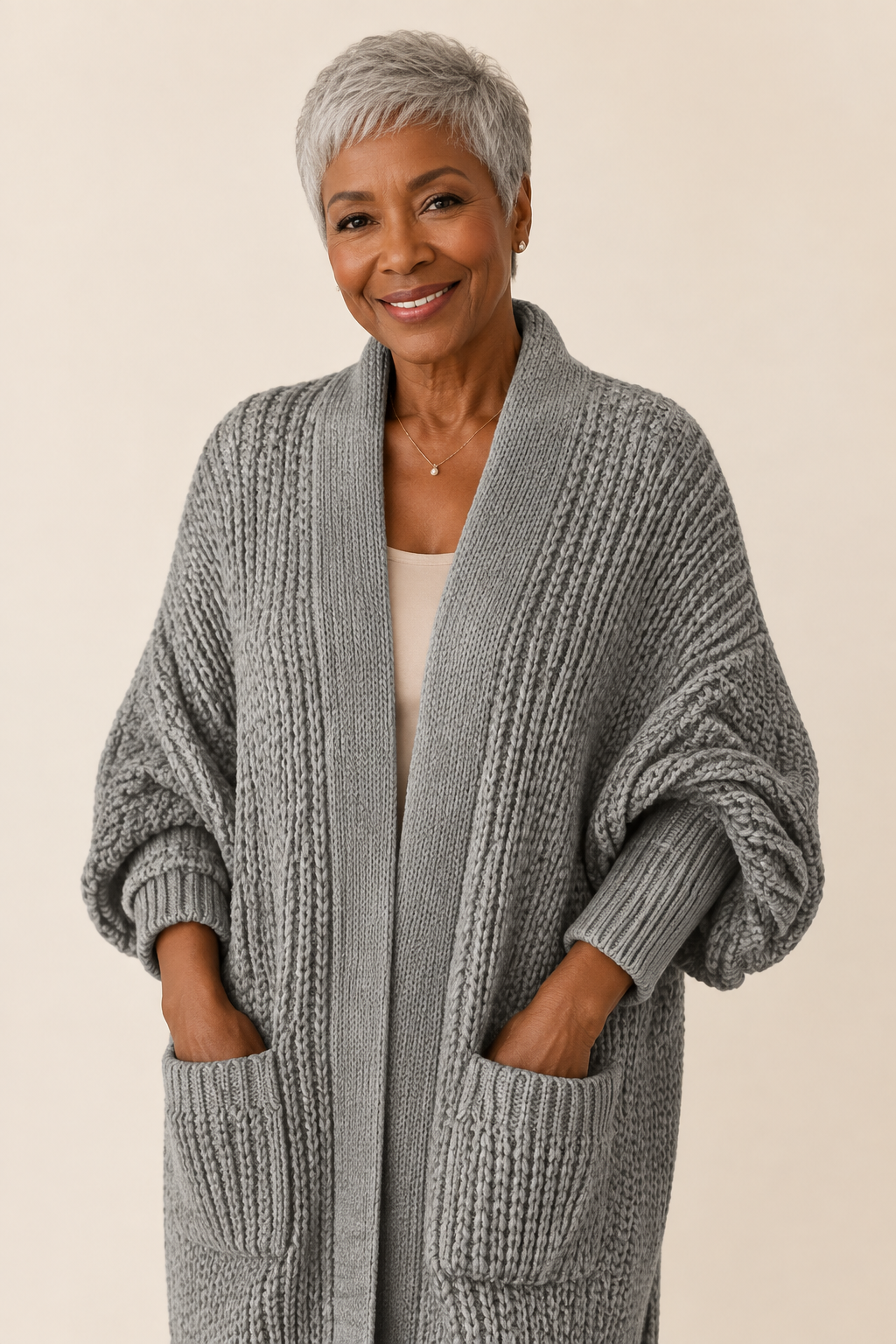 Stela graue lange Strickjacke an reifer Frau auf warmem beigem Hintergrund