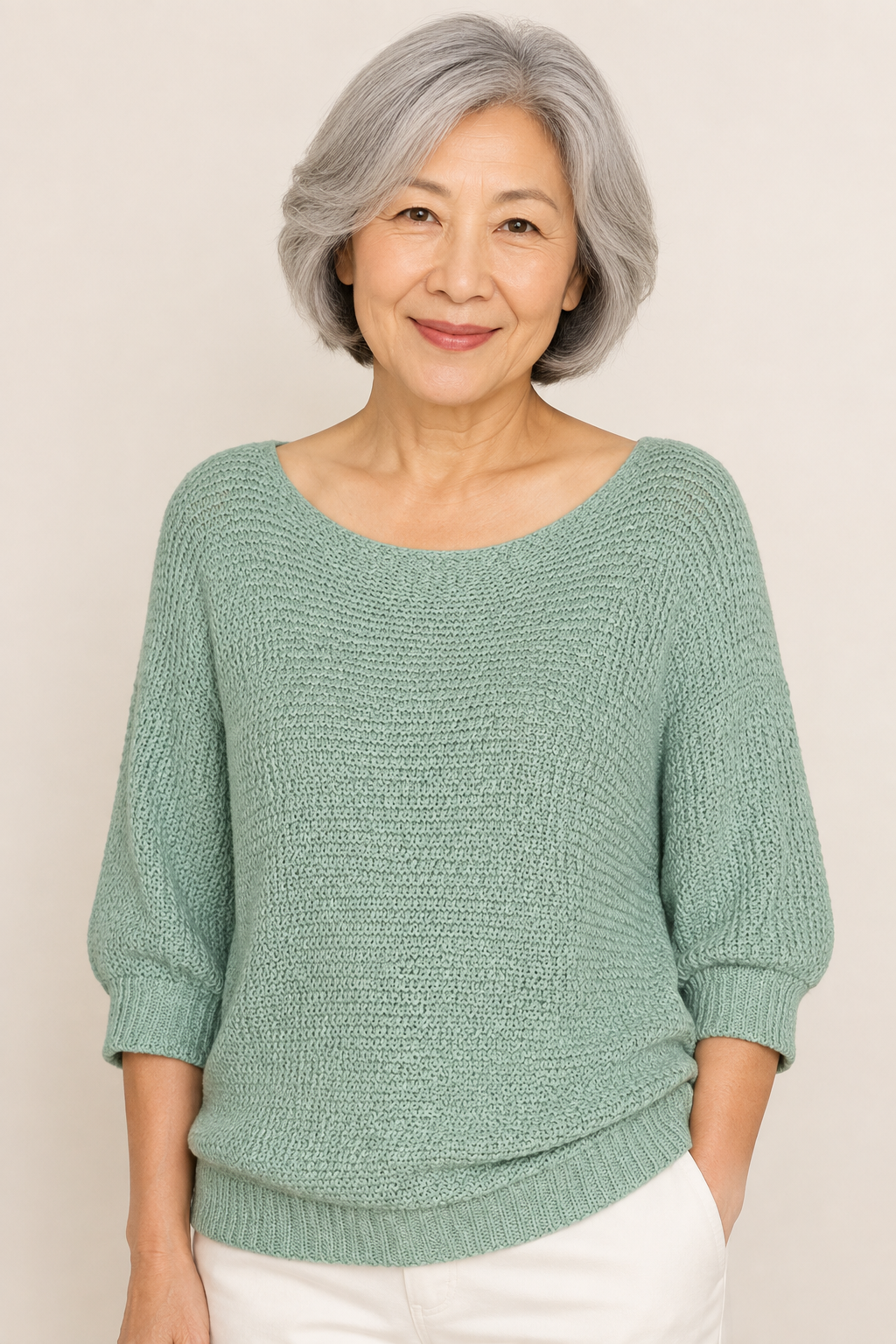 Teodora mintgrüner Strickpullover an reifer Frau auf warmem beigem Hintergrund
