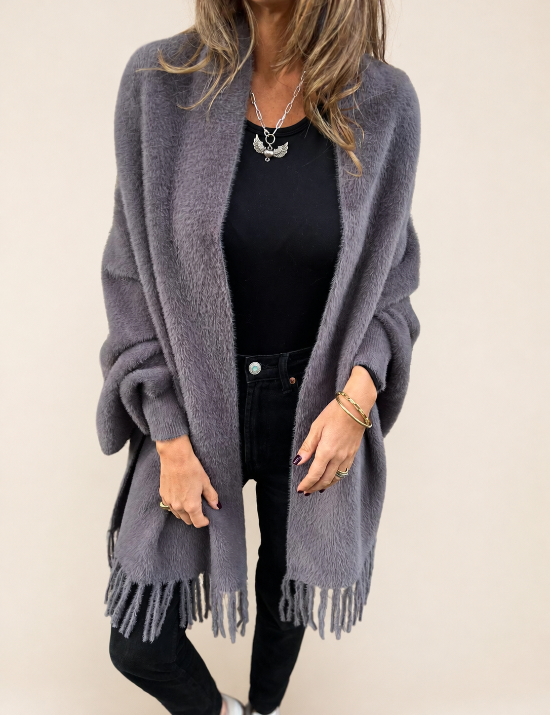 Warme lange graue Strickjacke auf warmem beigem Hintergrund