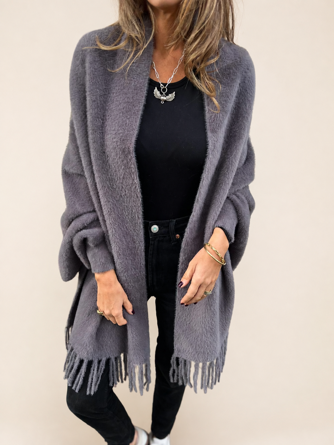 Warme lange graue Strickjacke auf warmem beigem Hintergrund